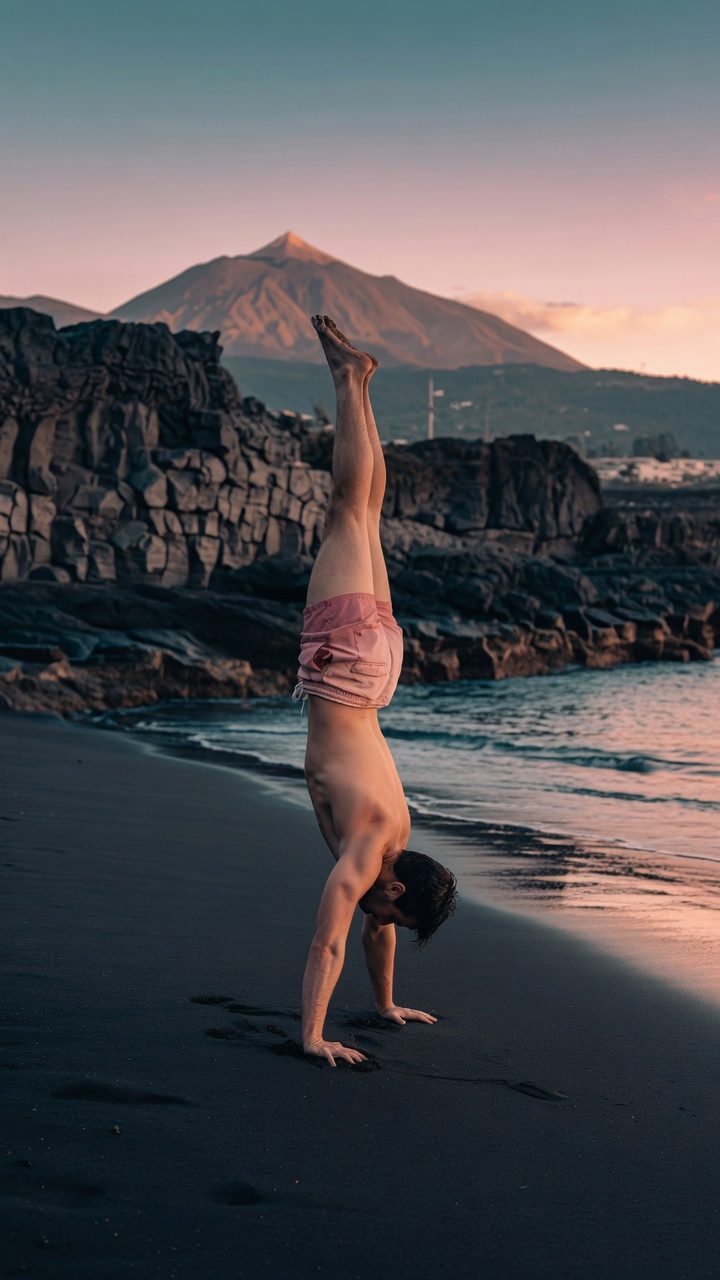 Ismael Cabo haciendo el pino en una playa de arena negra de Tenerife con el Teide al fondo